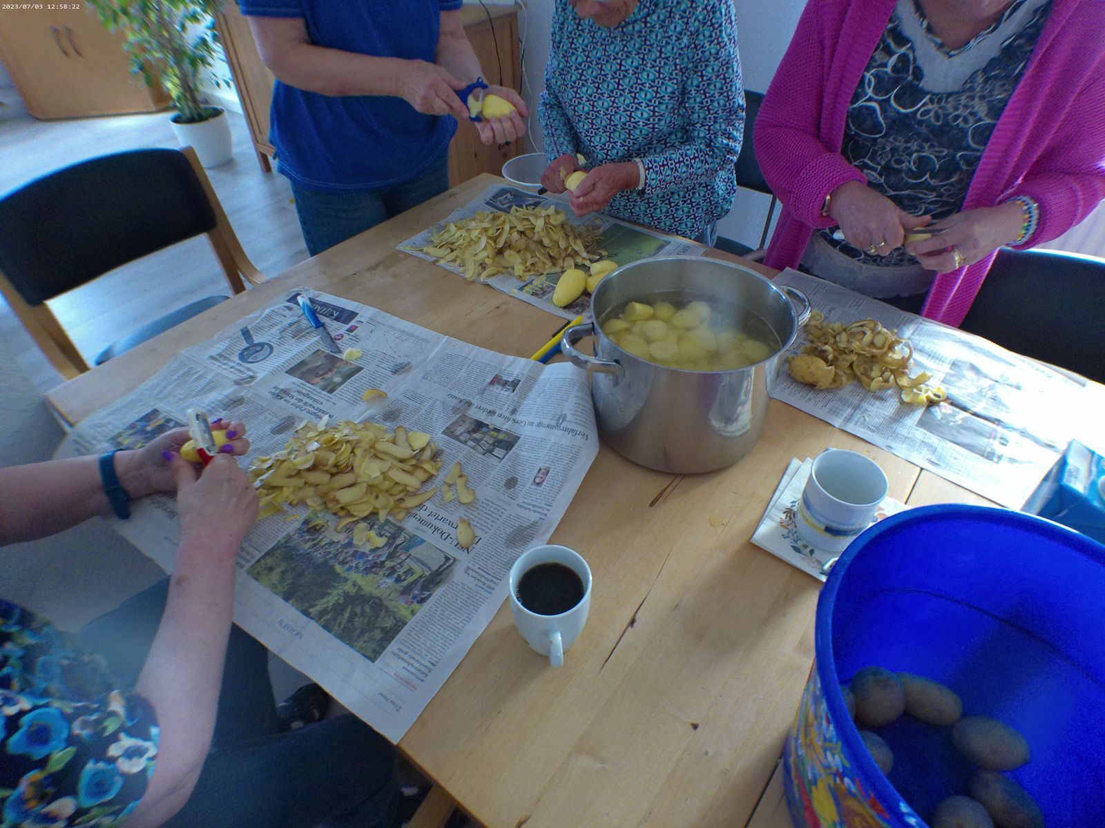 Mehrere Leute schälen gemeinsam Kartoffeln.